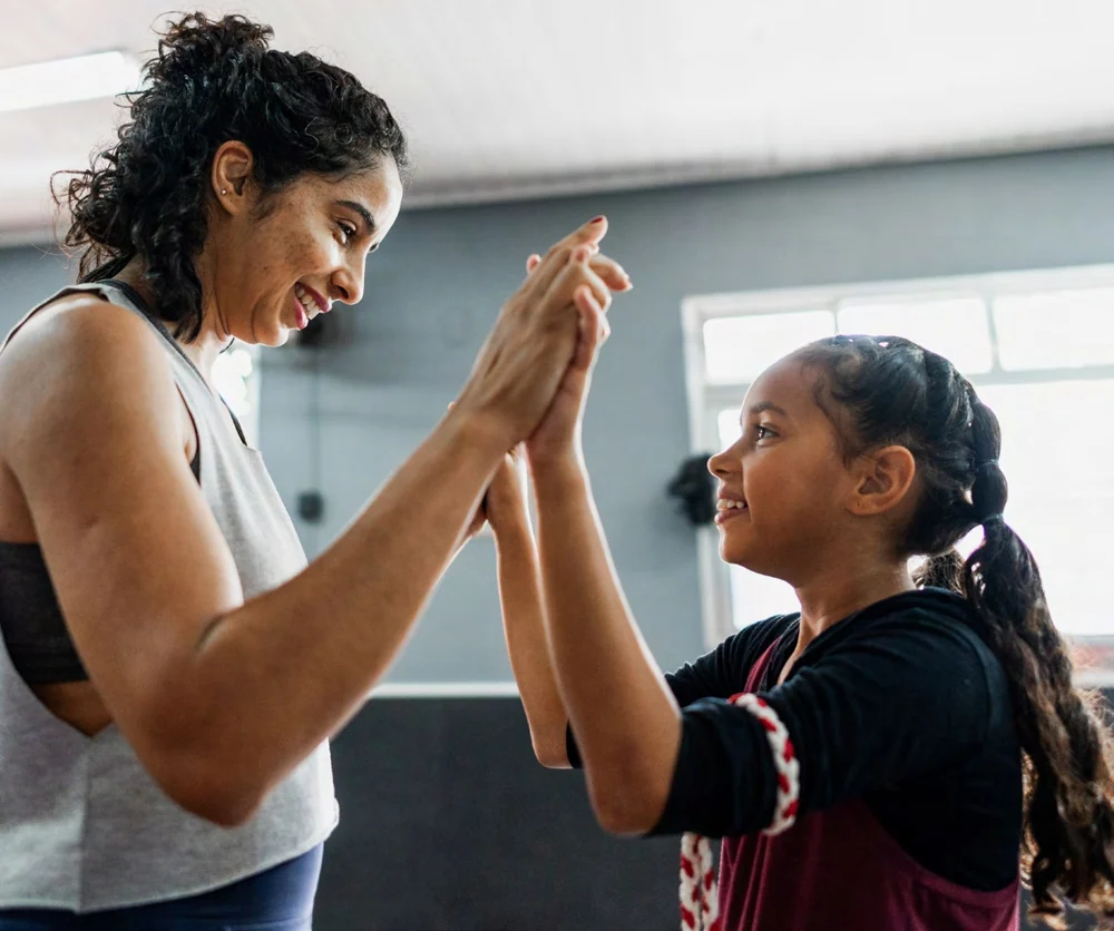 A coach and young participant sharing a high five